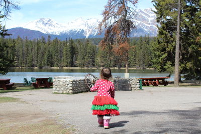 Rear view of baby girl walking on road towards lake