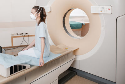 Patient wearing mask sitting in ct scan room