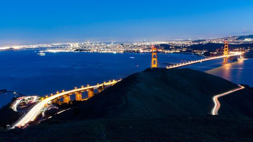 Illuminated bridge over river in city at night