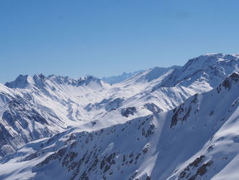 Scenic view of snowcapped mountains against clear blue sky