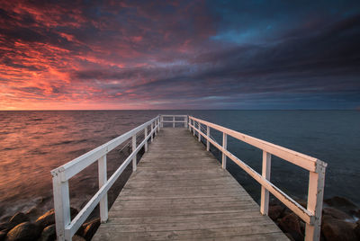 Pier over sea against sky during sunset