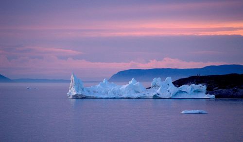 Icebergs in sea during sunset