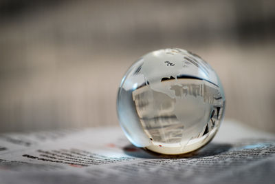 Close-up of crystal globe ball on newspaper