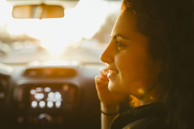 Smiling young woman traveling in car during sunset