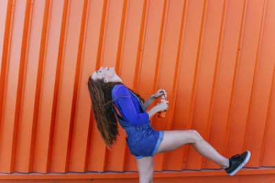 Side view of woman against orange wall