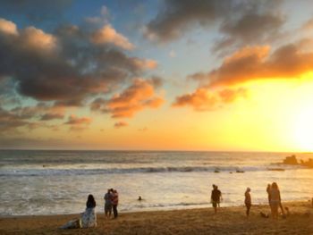 People playing on beach at sunset