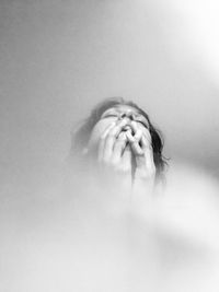 Portrait of woman covering face against wall