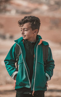 Young man looking away while standing outdoors