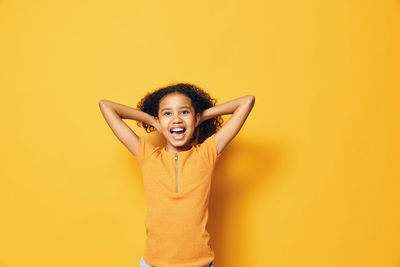 Portrait of young woman standing against yellow background