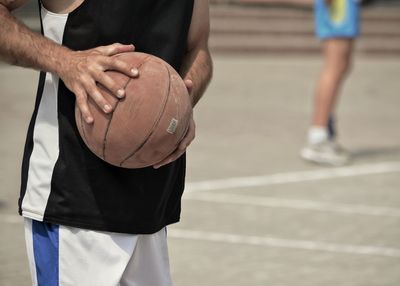Midsection of man holding ball while standing on table