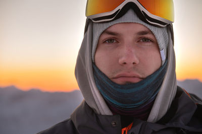 Portrait of a pensive skier in the mountains at sunset. a young man looks at the camera while