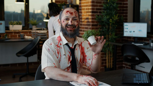 Happy businessman in zombie character at office