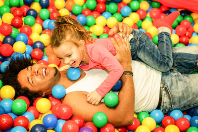 Happy father and daughter playing with multi colored balls in pool