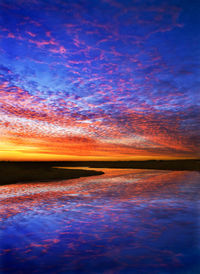 Scenic view of lake against dramatic sky during sunset