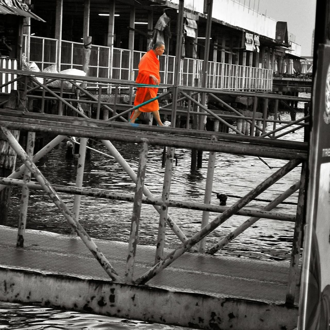 REAR VIEW OF MAN WORKING ON METAL RAILING