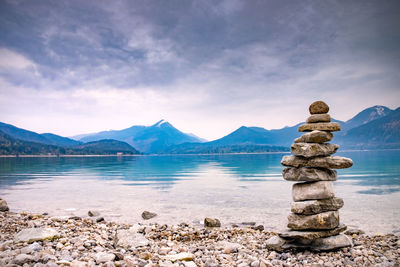 Pile stones on beach. rock heap of gray dolomite pebbles close to alpine lake, mountains silhouettes