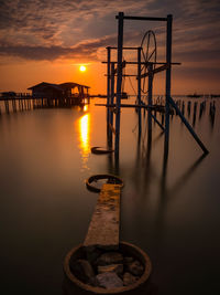 Pier over lake against sky during sunset