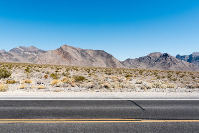 Road by desert against clear sky