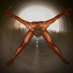 Full length of naked man bending in large pipe