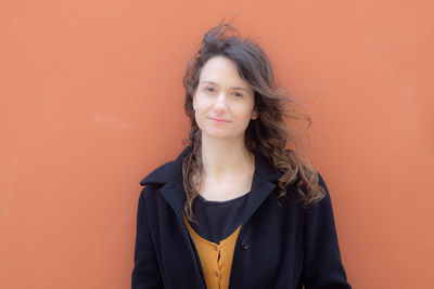 Portrait of beautiful young woman against orange background