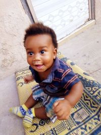 High angle portrait of smiling boy sitting outdoors