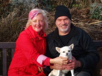 Portrait of happy mature couple with dog sitting at park