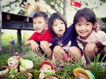 Siblings crouching by figurines at park