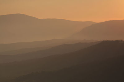 Silhouette landscape against mountains during foggy weather