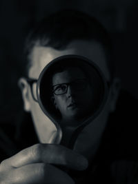 Portrait of man looking through magnifying glass in darkroom