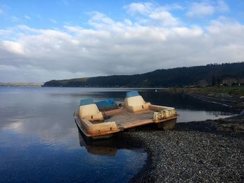 Boat moored on lake against sky