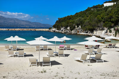 Chairs on beach by sea against sky