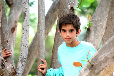 Portrait of boy standing on tree trunk