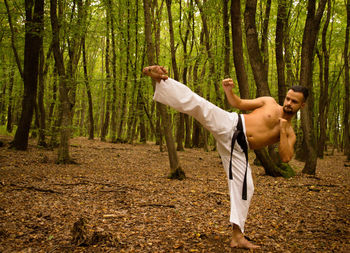 Side view of young man standing in forest