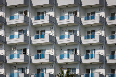 A white residential building with flat, identical balconies with ripped air conditioners