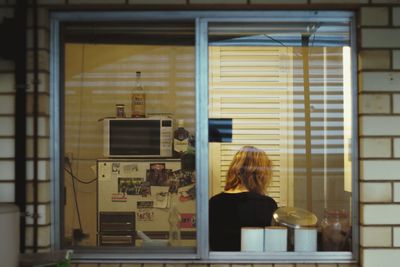 Rear view of woman standing by window