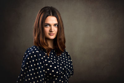 Portrait of young woman standing against wall