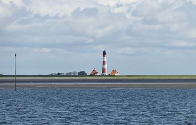 Lighthouse by sea against sky