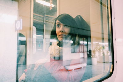 Thoughtful woman traveling in train seen through window