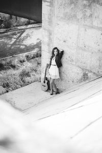 Full length portrait of woman standing against wall