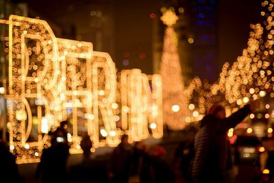 People on illuminated christmas lights at night