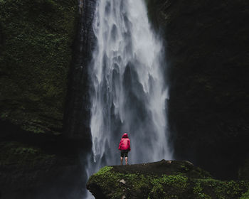 Rear view of woman standing against waterfall