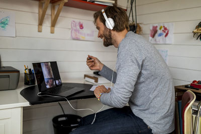 Smiling man talking with girlfriend on video call through laptop at home