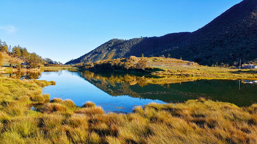 Scenic view of lake and mountains against clear blue sky