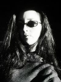 Close-up of young woman against black background