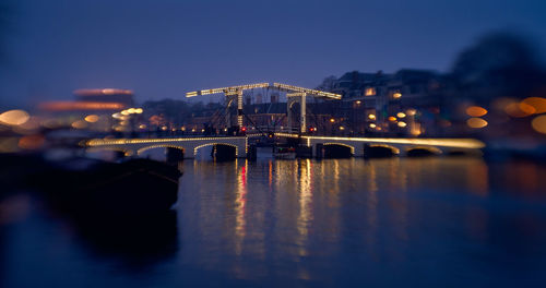 Illuminated bridge over river against sky at night