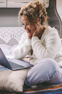 Young woman using laptop while sitting on sofa at home