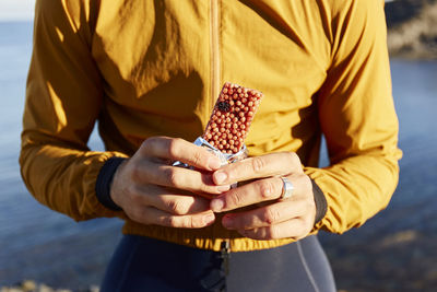 Hands of cyclist holding energy bar on sunny day