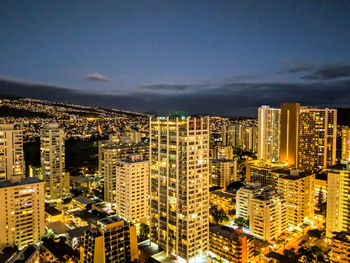 Illuminated buildings in city against sky at night