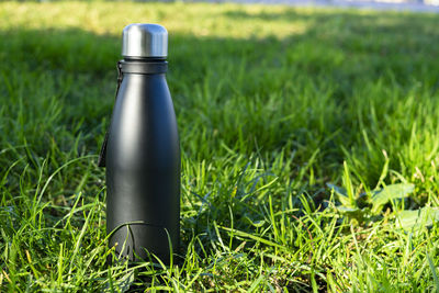 Black travel thermos on a green grassy background.