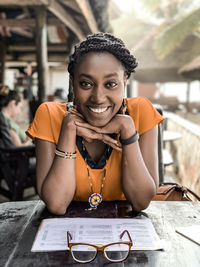 Portrait of smiling young woman sitting at table